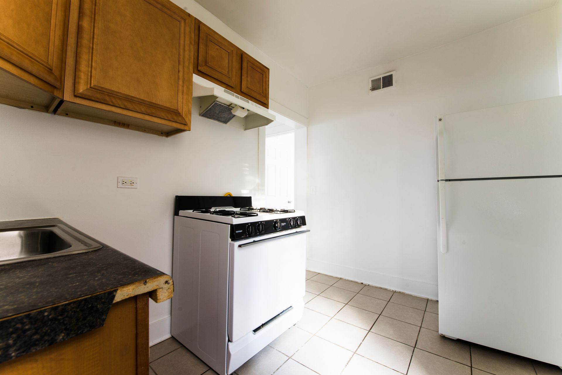 Kitchen with white appliances, wooden cabinets, and dark countertop.