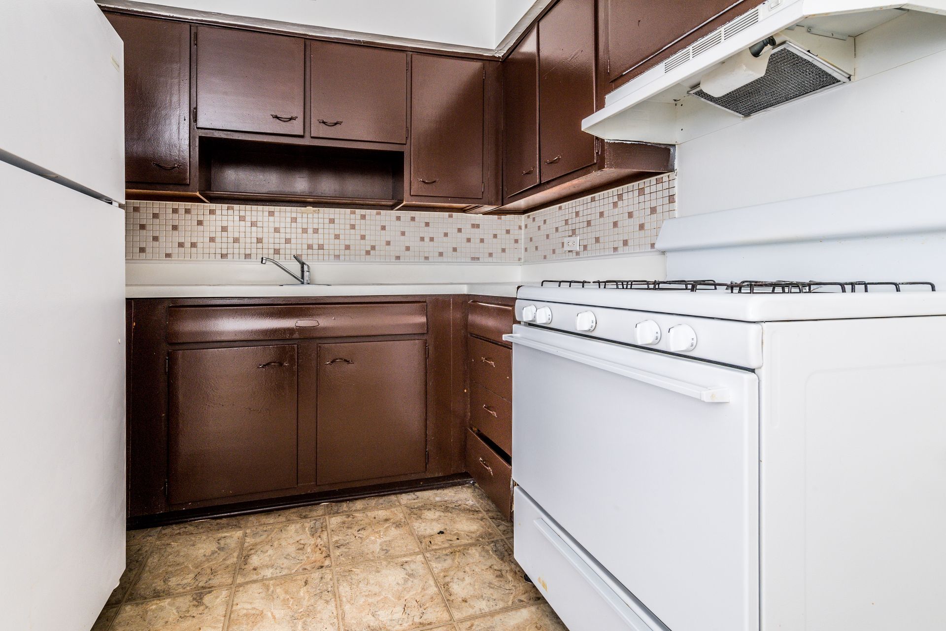 Brown kitchen cabinets and white appliances in a small kitchen.