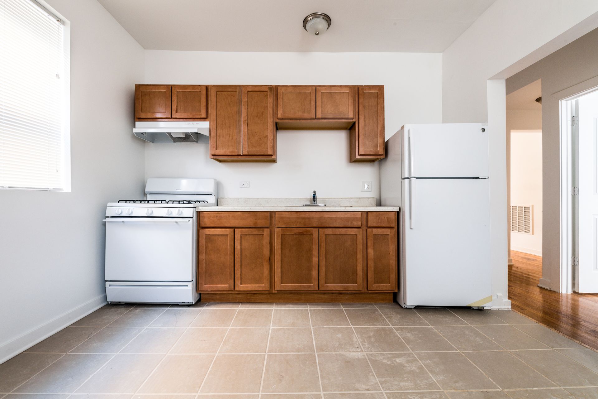 Kitchen with brown cabinets, white appliances, and tiled floor.