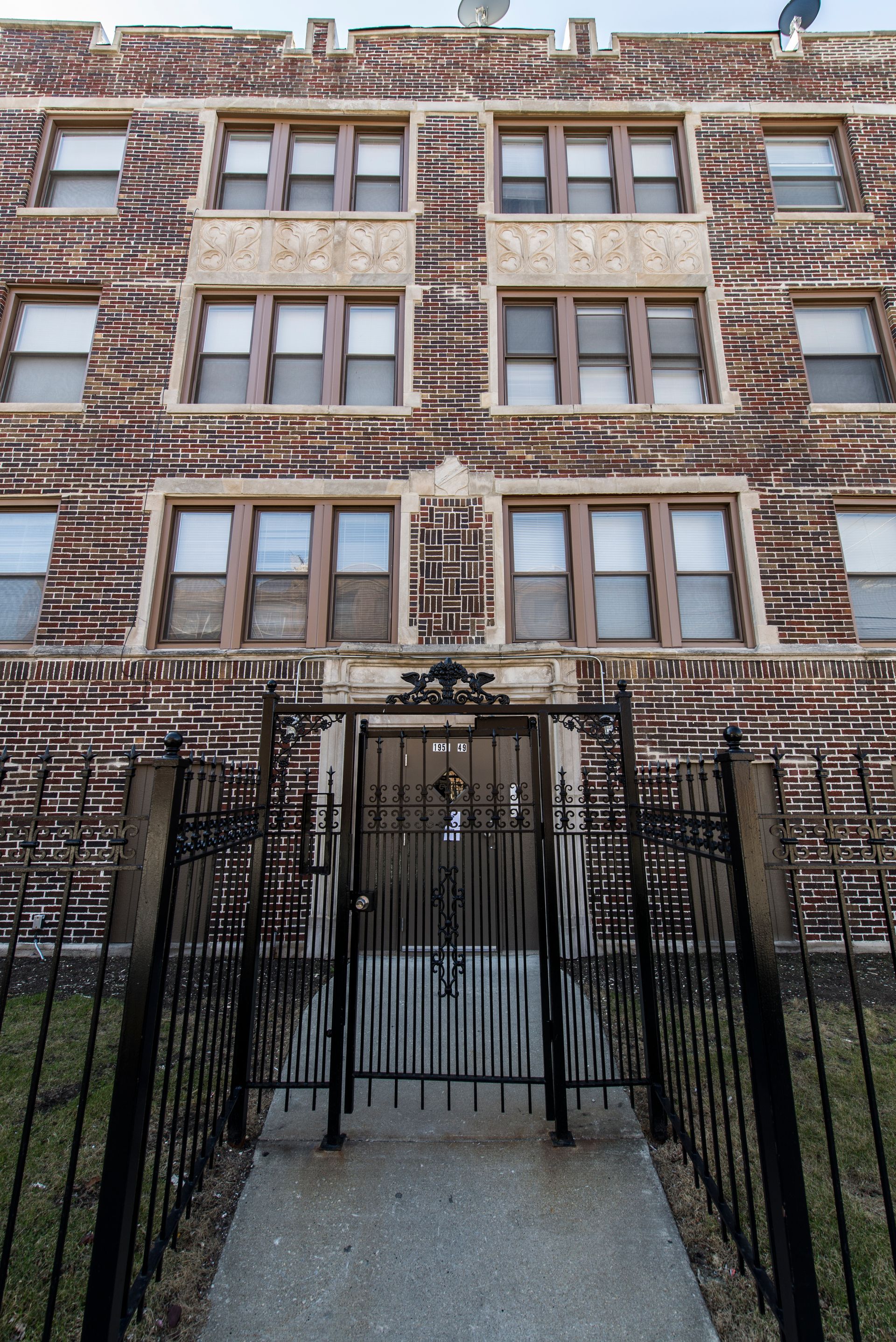 Brick apartment building with ornate entrance gate and multiple windows.