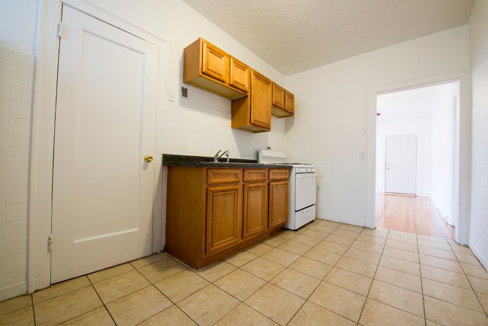 Kitchen with upper and lower wooden cabinets, sink, and an open doorway.
