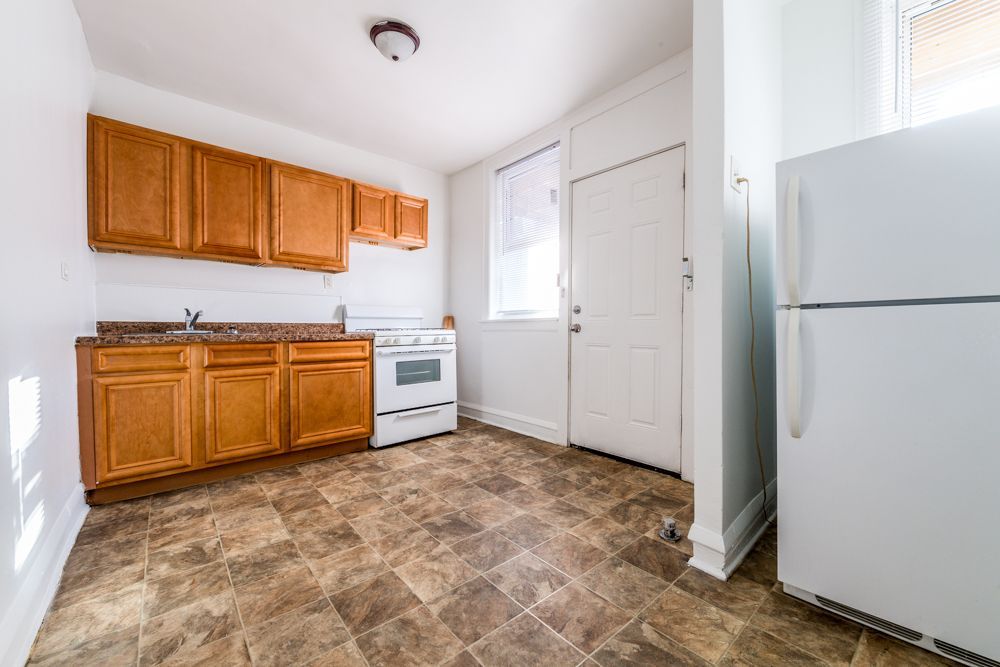 Kitchen with wooden cabinets, white appliances, and brown flooring.