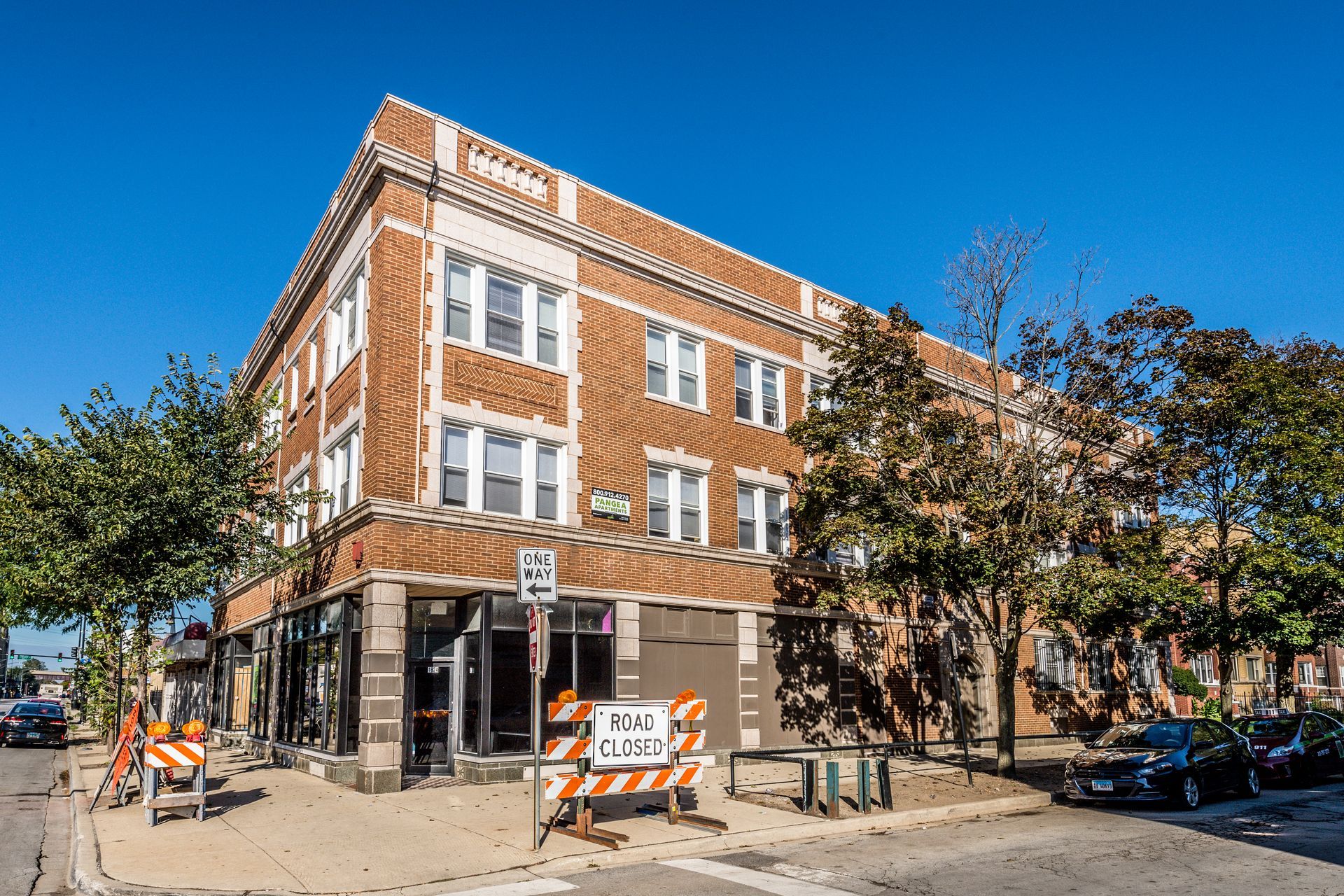 Multi-story brick building on a street corner, with boarded-up storefronts and