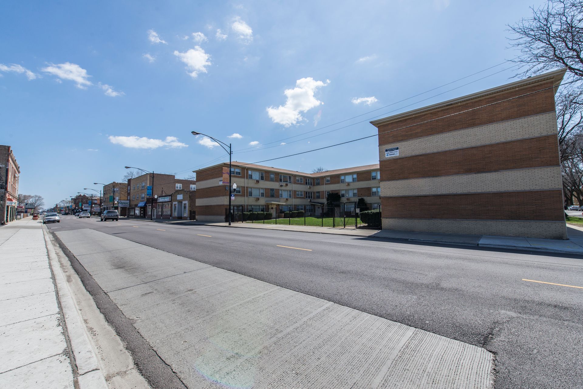 Street view with multi-story brick buildings, blue sky, and a road.