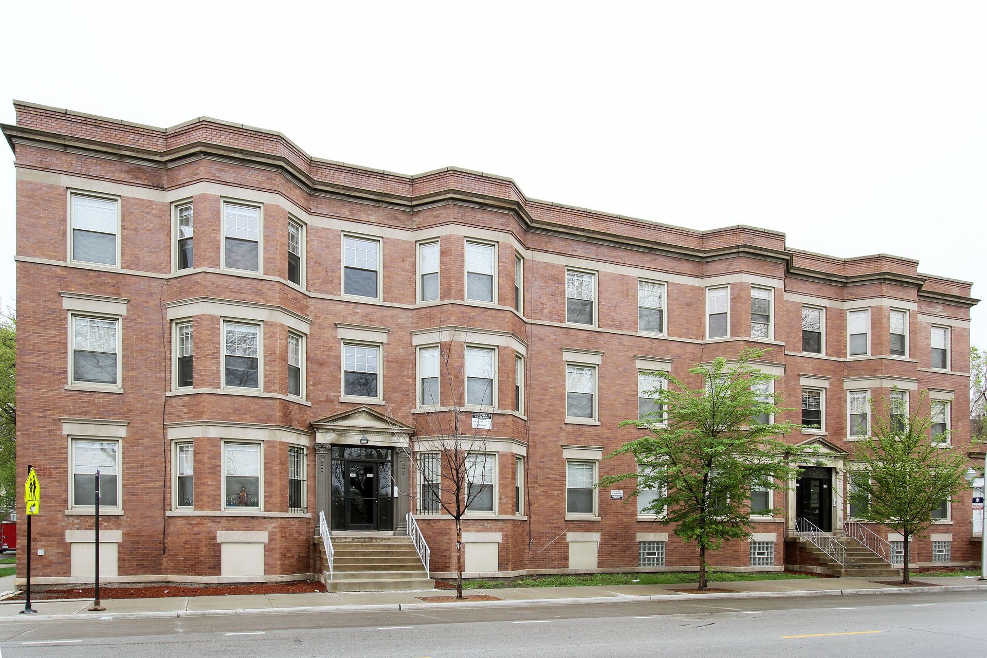 Brick apartment building with multiple windows and decorative trim.