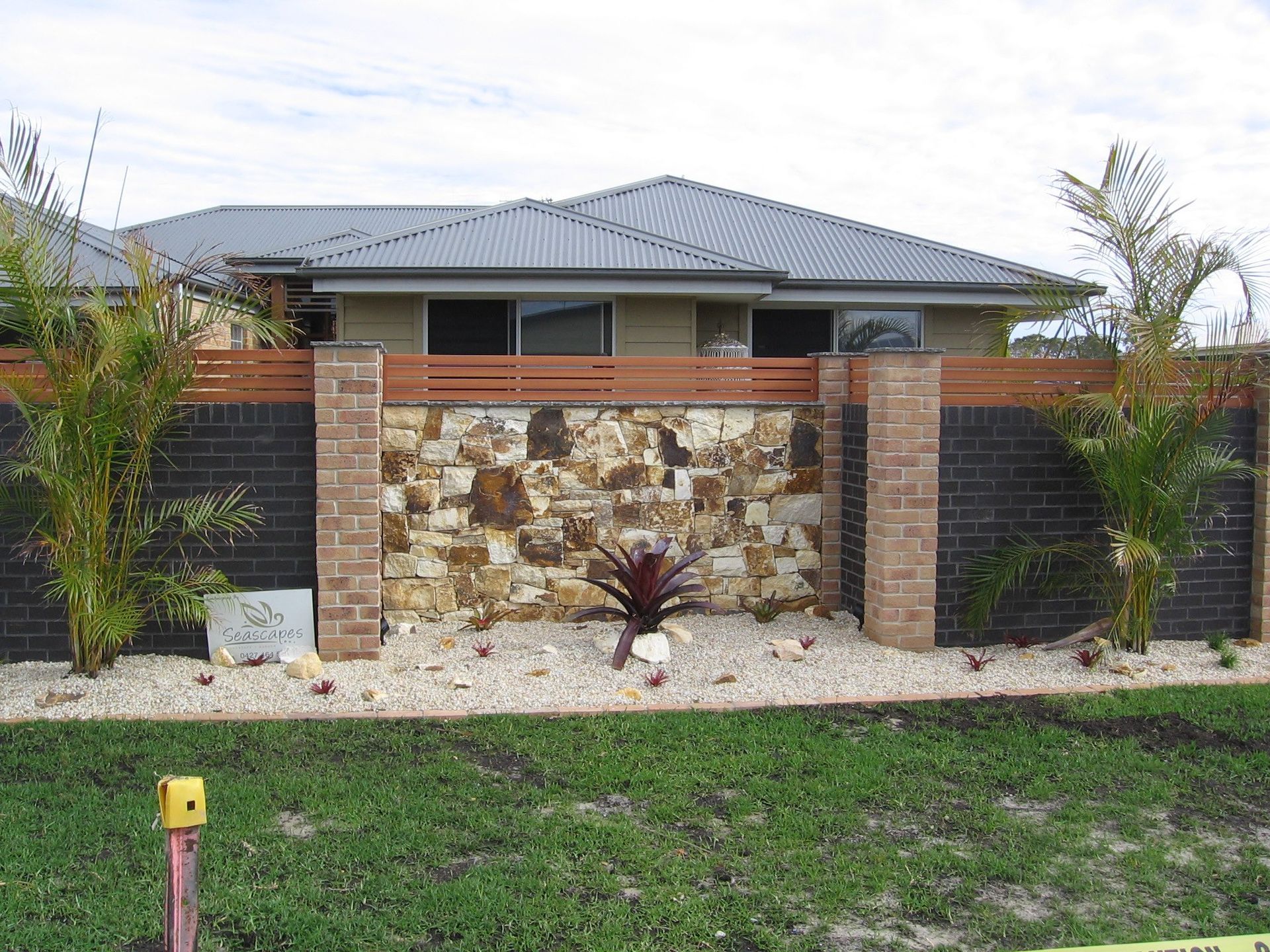 A House With a Stone Wall and a Brick Fence in Front of It — Seascapes Landscape Construction in Kendall, NSW