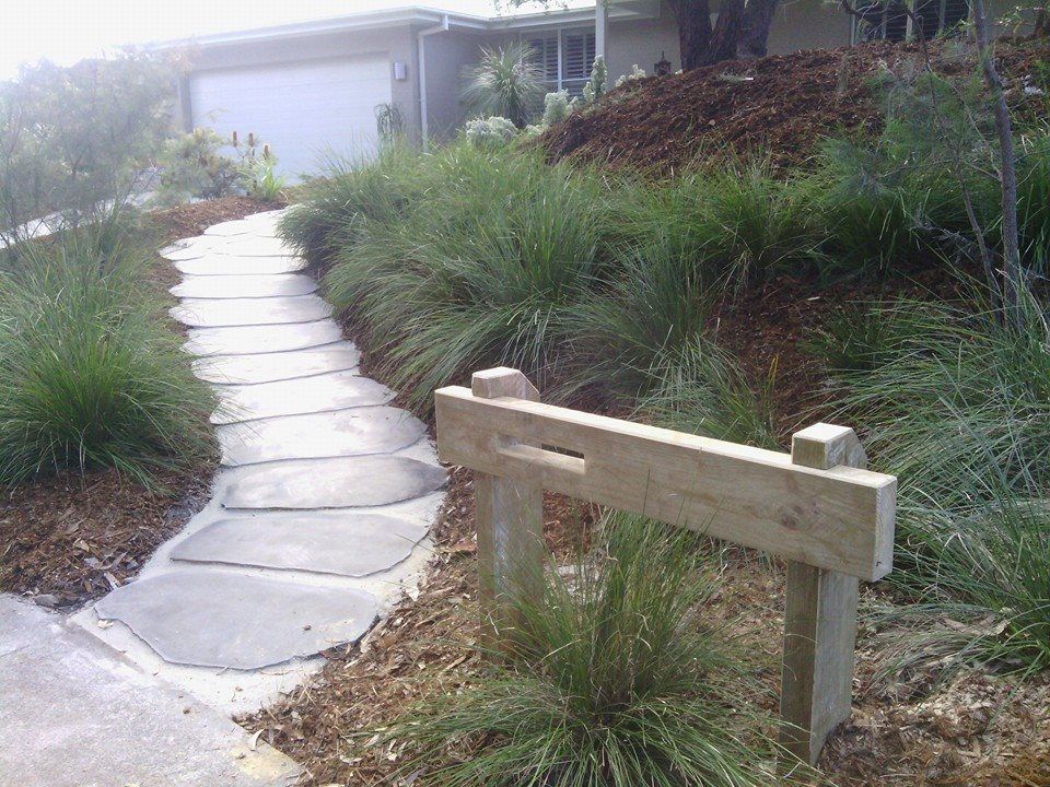 A Stone Walkway Leading to a House With a Wooden Fence — Seascapes Landscape Construction in Kendall, NSW