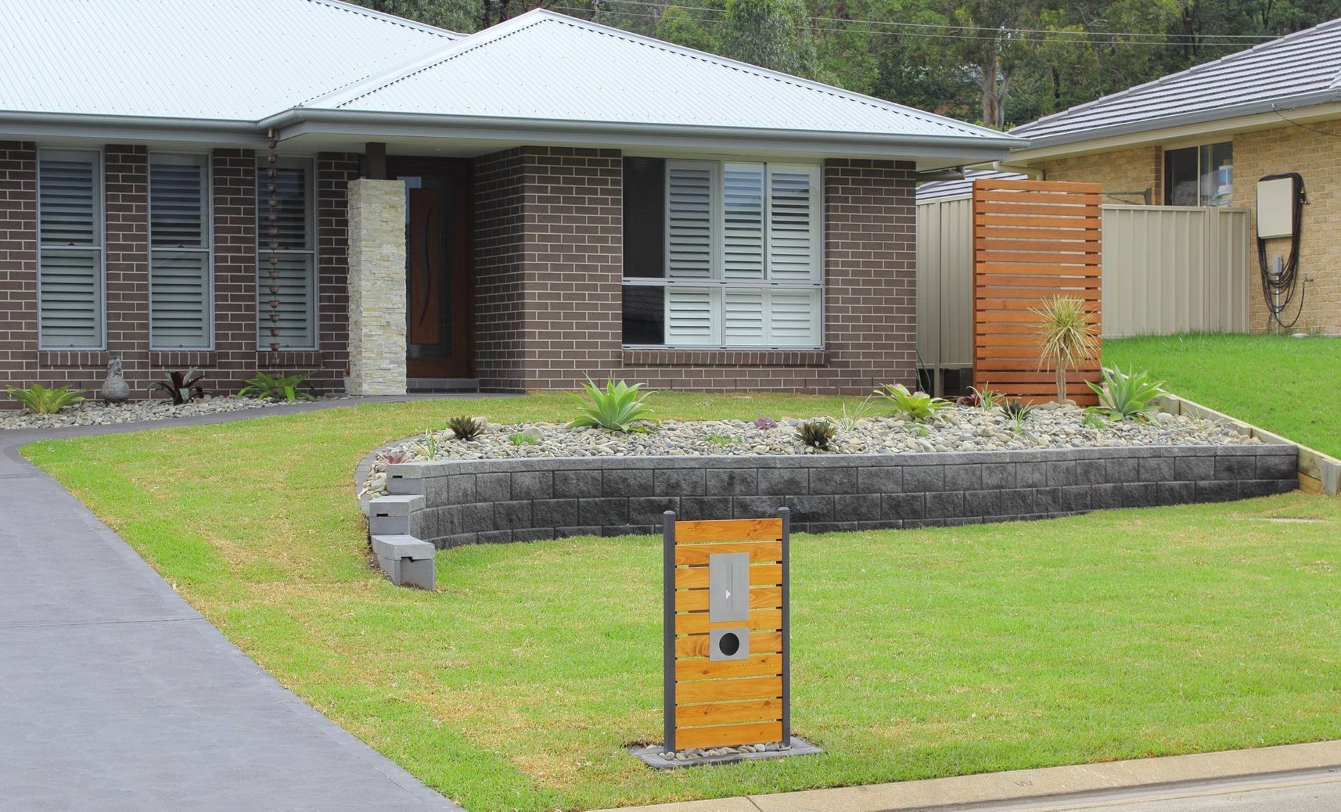A Brick House With a Lush Green Lawn in Front of It — Seascapes Landscape Construction in Kendall, NSW