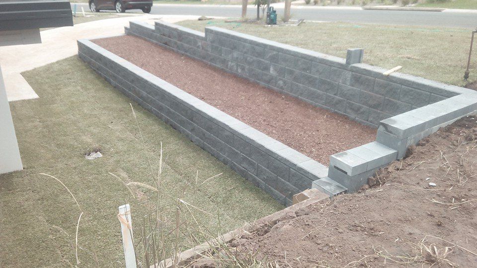 A Brick Wall is Being Built in a Yard Next to a Road — Seascapes Landscape Construction in Kendall, NSW