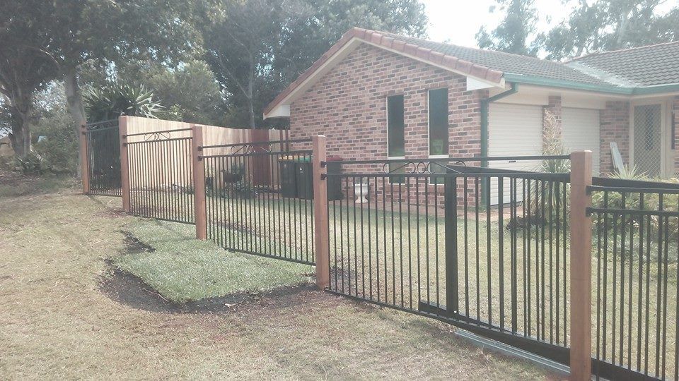 A Brick House With a Metal Fence in Front of It — Seascapes Landscape Construction in Kendall, NSW