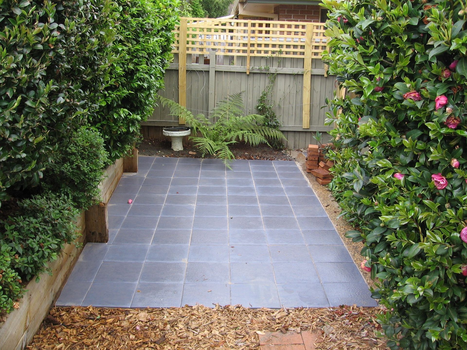 A Small Garden With a Tiled Floor and a Fence — Seascapes Landscape Construction in Kendall, NSW
