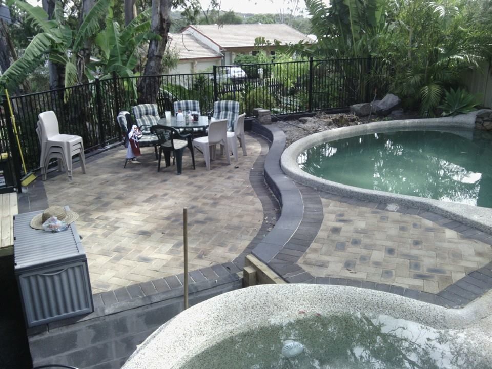 A Patio With a Table and Chairs Next to a Pool — Seascapes Landscape Construction in Kendall, NSW