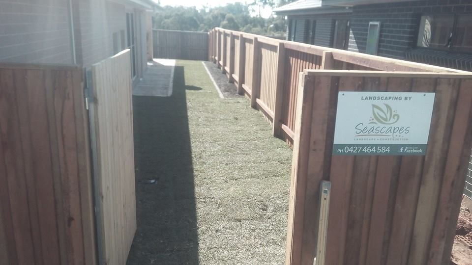 A Wooden Fence With a Sign on It That Says Gardens — Seascapes Landscape Construction in Kendall, NSW