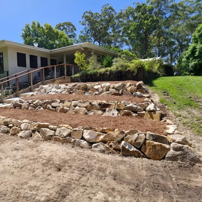 A House With Stairs Made of Rocks in Front of It — Seascapes Landscape Construction in Lake Cathie, NSW