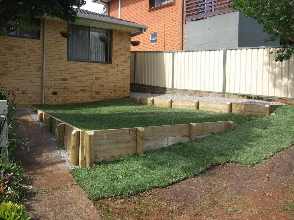 A Brick House With a White Fence and a Lush Green Lawn — Seascapes Landscape Construction in Kendall, NSW