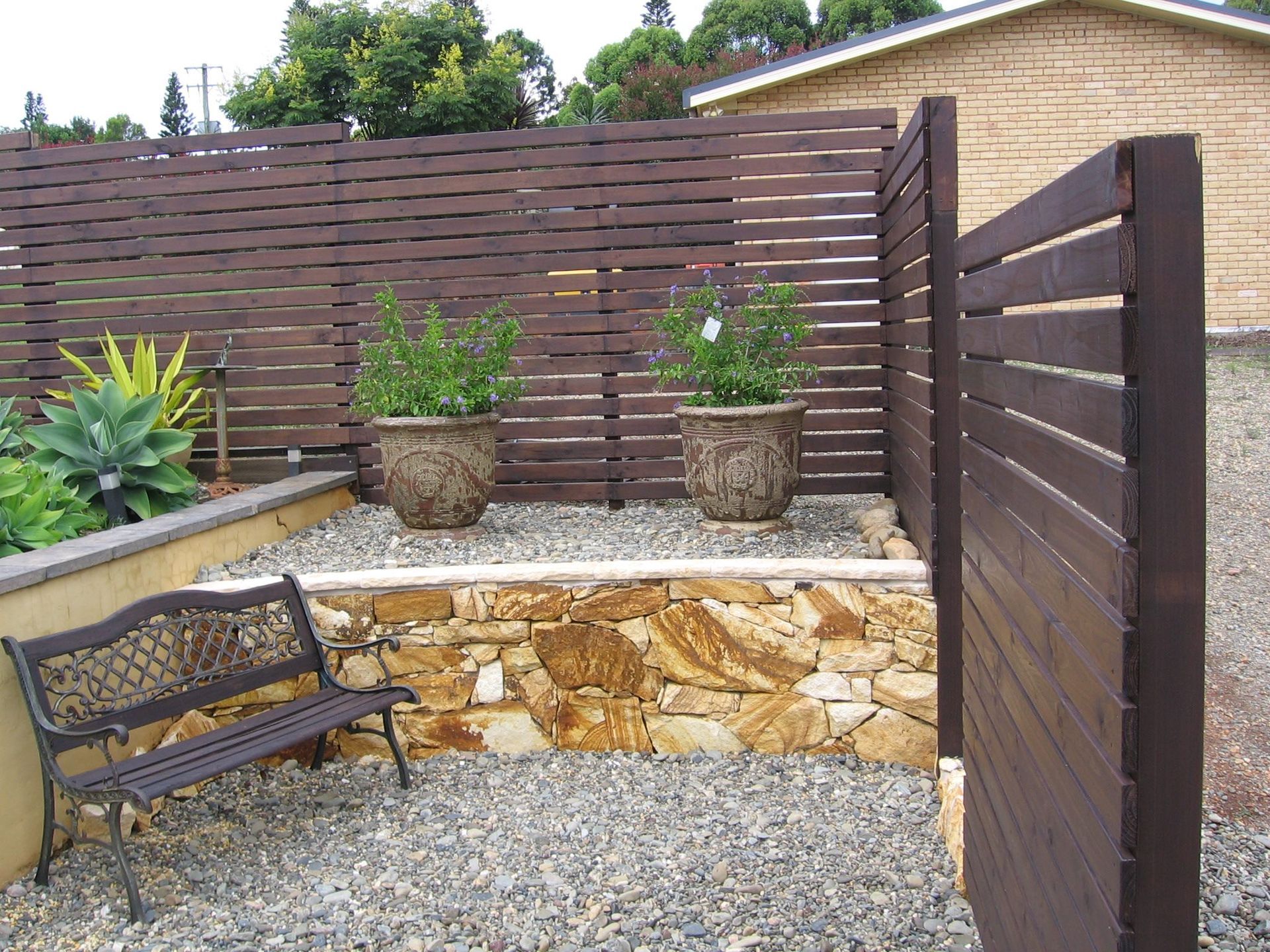 A Wooden Fence With Potted Plants Behind It — Seascapes Landscape Construction in Kendall, NSW