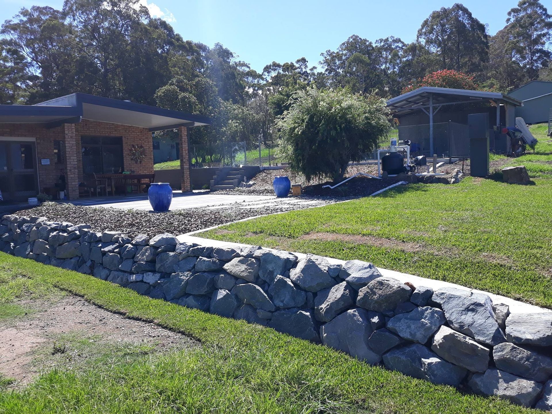 A House With a Stone Wall in Front of It — Seascapes Landscape Construction in Kendall, NSW
