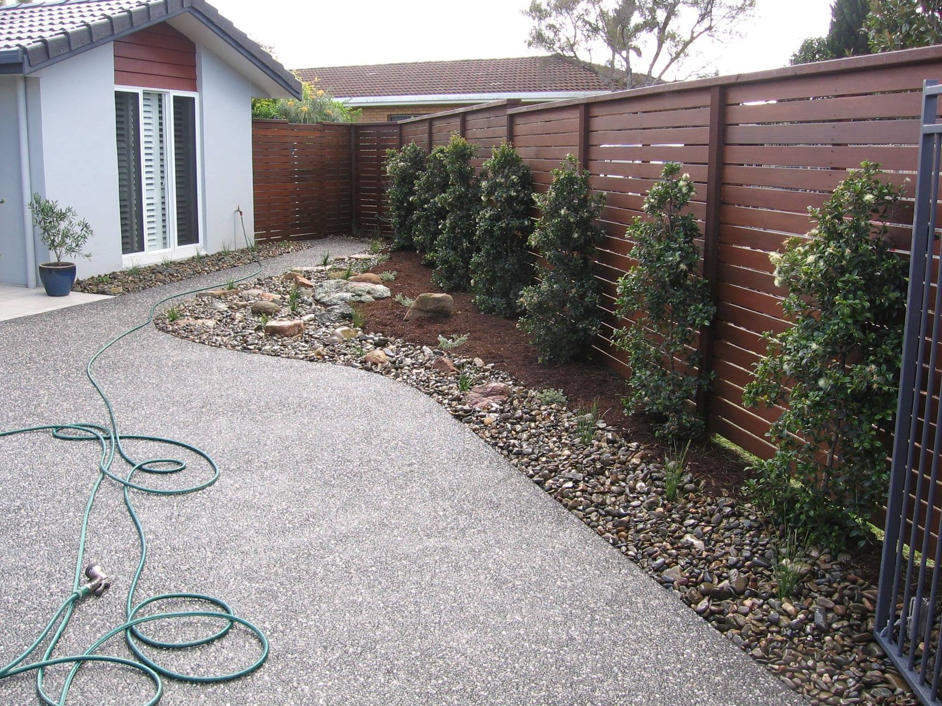 A Hose is Laying on the Ground in Front of a House — Seascapes Landscape Construction in Kendall, NSW