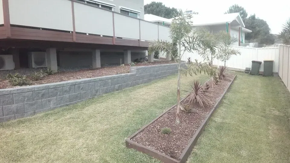 A Lush Green Lawn in Front of a House With a Deck — Seascapes Landscape Construction in Kendall, NSW