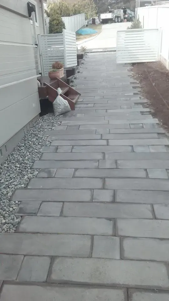 A Brick Walkway Leading to a House With a White Fence — Seascapes Landscape Construction in Wauchope, NSW
