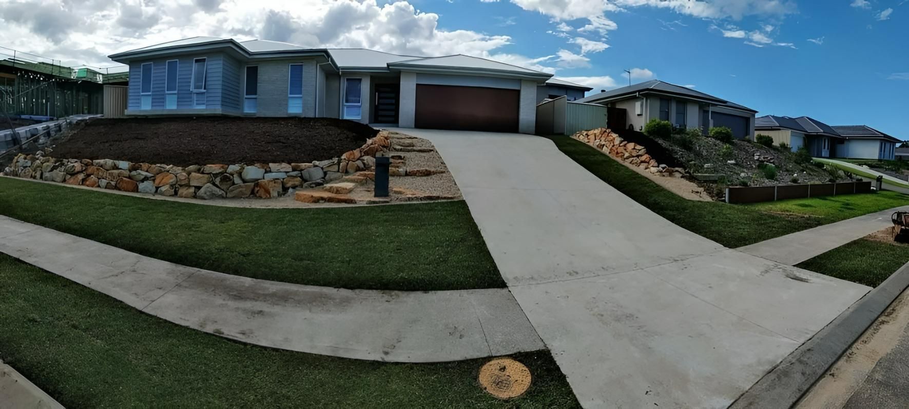 A Large House is Sitting on Top of a Hill in a Residential Area — Seascapes Landscape Construction in Kendall, NSW