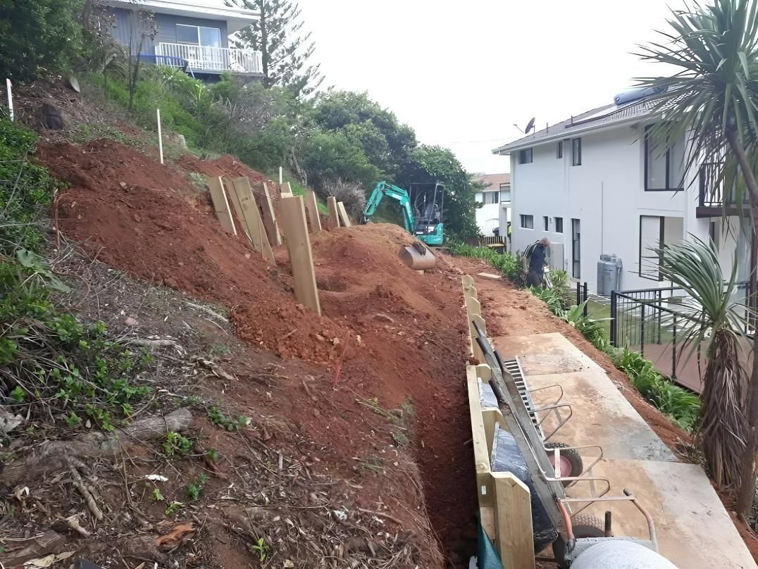 A Large Pile of Dirt is Sitting on Top of a Hill Next to a House — Seascapes Landscape Construction in Kendall, NSW