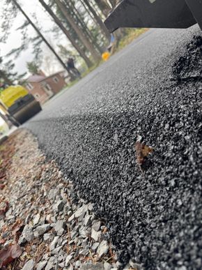 Close-up of wet black asphalt beside a gravel shoulder on a rainy roadside