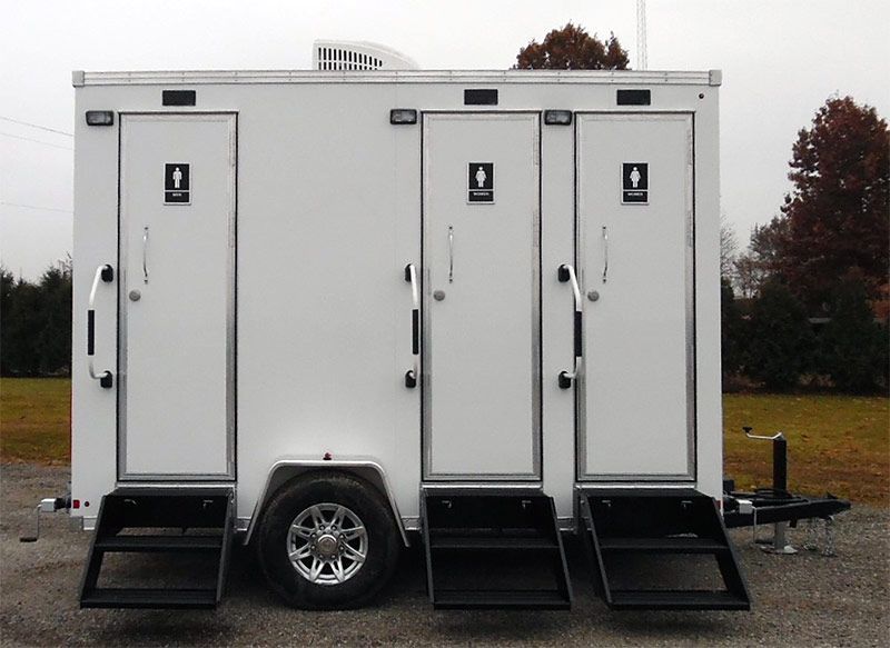 A white trailer with three toilets on it