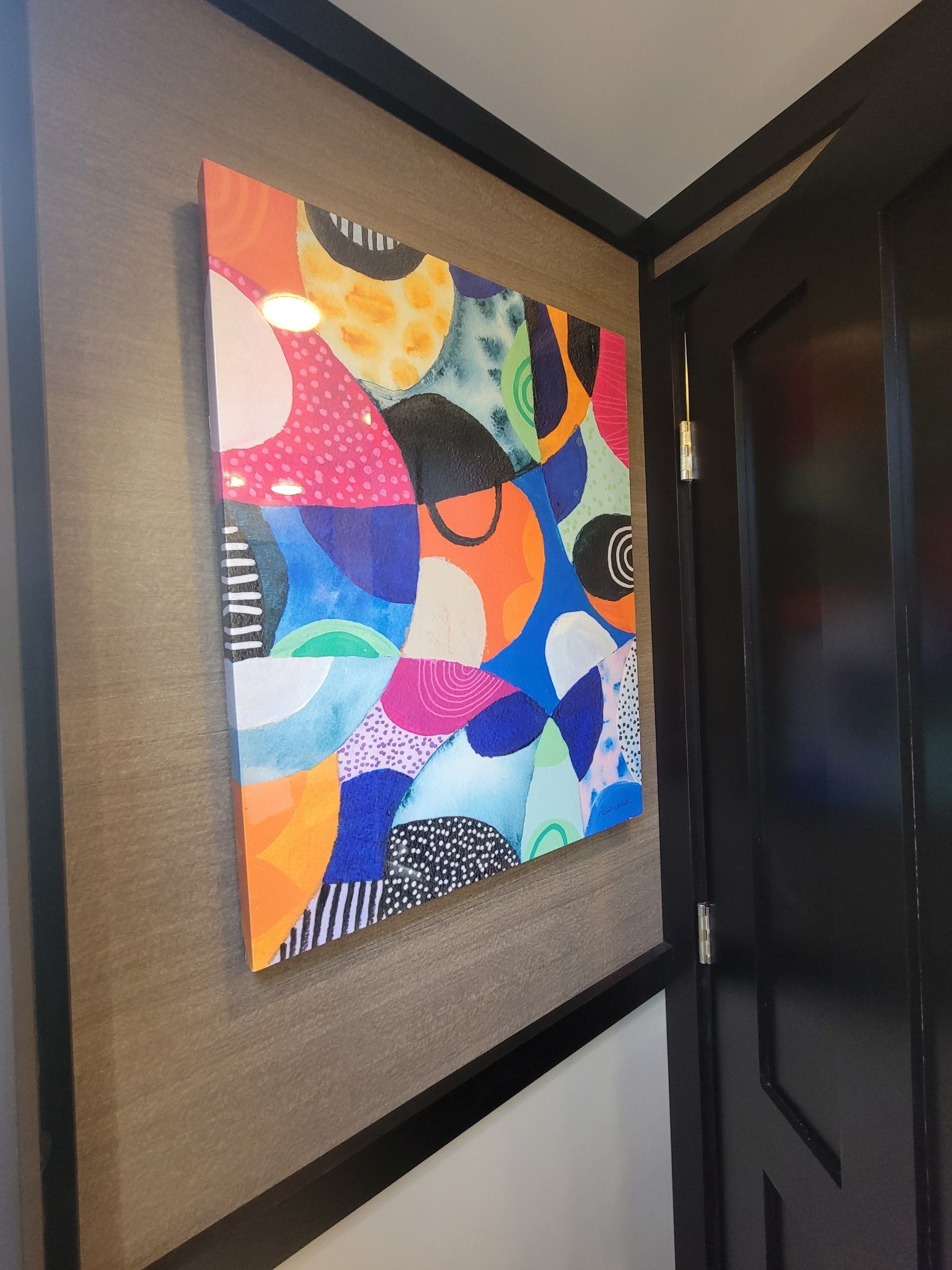 A colorful painting is hanging on a wall next to a door