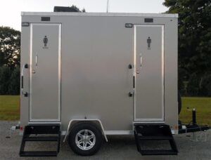 A trailer with two toilets on it is parked in a field