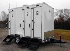 A white trailer with stairs attached to it is parked in a field