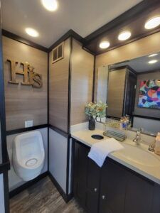 Bathroom with a urinal and a sink and the word his on the wall