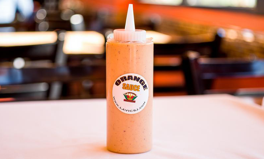 A bottle of orange sauce is on a table in a restaurant