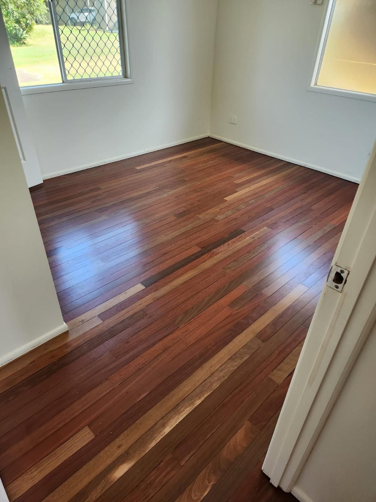 A Bedroom with Hardwood Floors and A Window — Finish It Floor Sanding in Bucca, QLD
