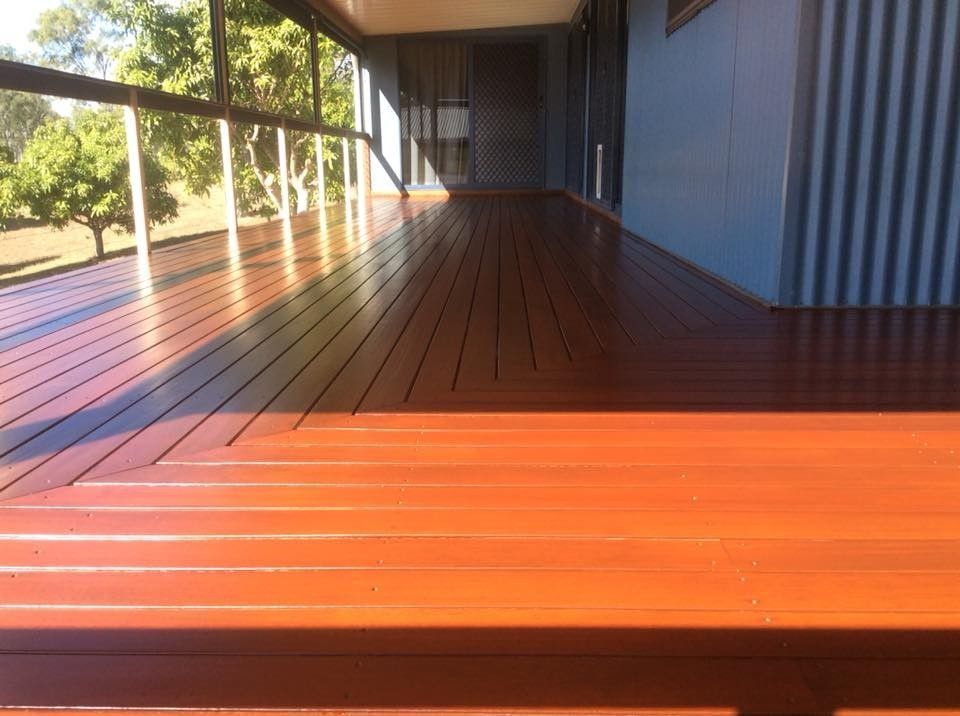 A Wooden Deck with A Blue Building in The Background — Finish It Floor Sanding in Bucca, QLD