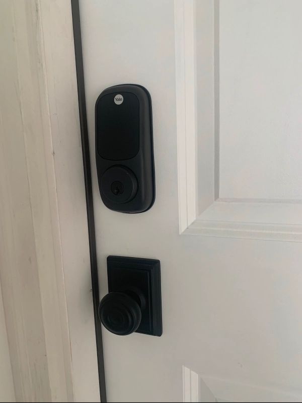 Black smart lock and doorknob on a white door.