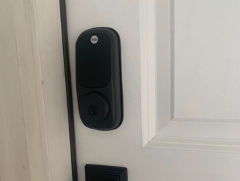 Black Yale smart lock installed on a white door.