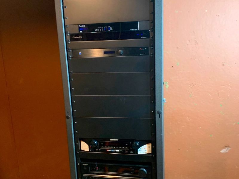 A black equipment rack containing electronic devices against an orange wall.
