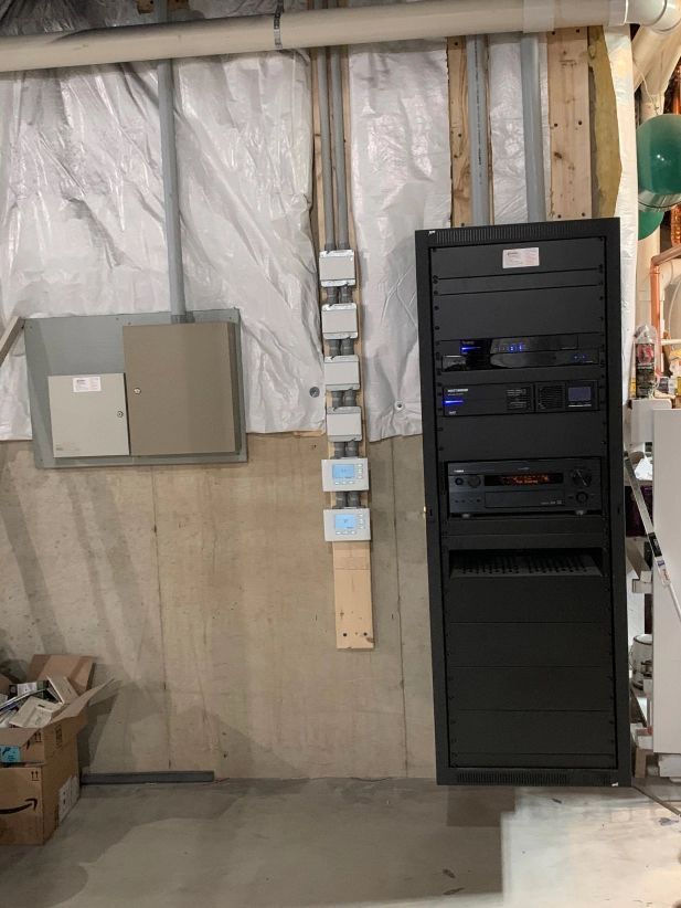 Basement wall with equipment rack, electrical boxes, and security system panel.
