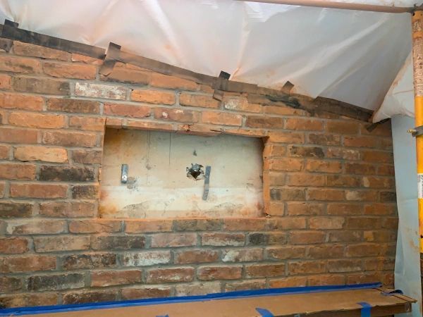 Brick wall with a rectangular opening; construction in progress.