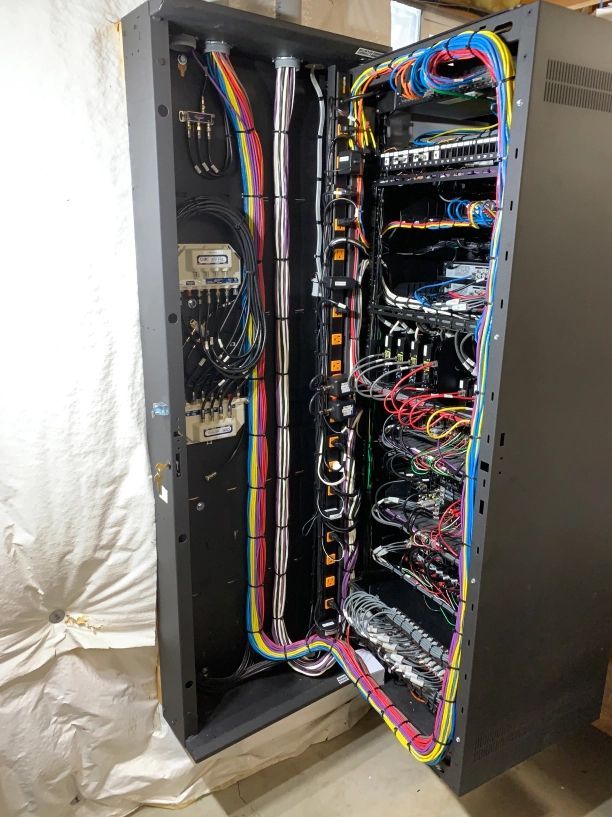 Open black server rack with multiple colored wires and equipment visible.