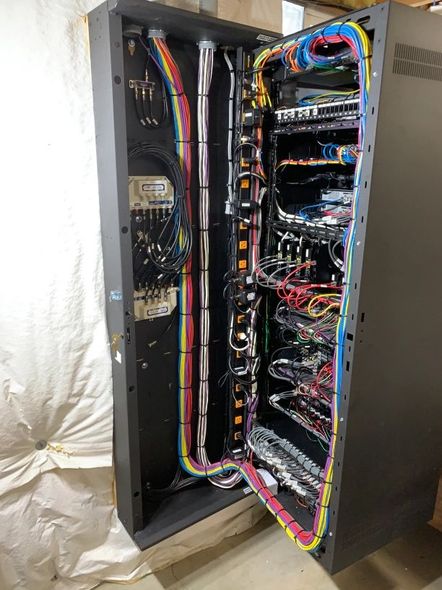 Black server rack with open doors, revealing organized wiring and electronic components.