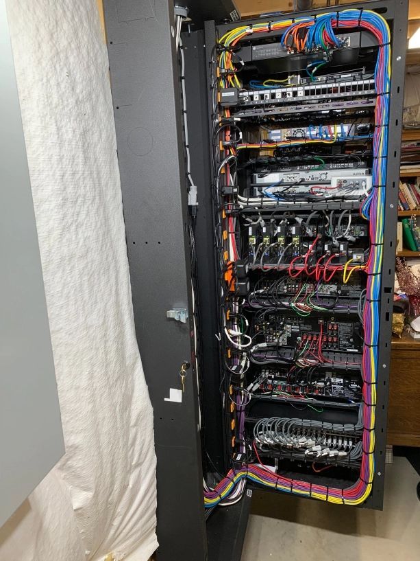Server rack with open door, filled with networked devices and colorful wiring.