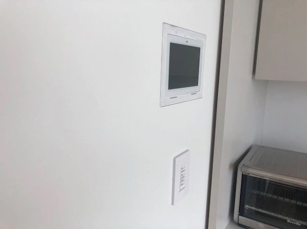 White wall with built-in tablet, light switch, and toaster oven in the corner.