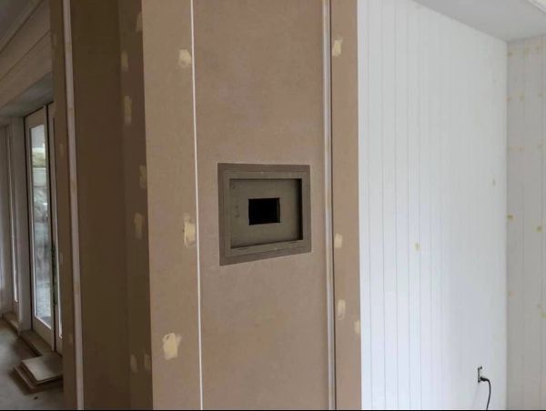 Interior wall with recessed square opening, tan and white. Unfinished construction with visible drywall seams.