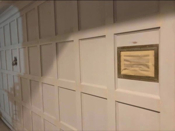 White paneled wall with a framed document set into the paneling.