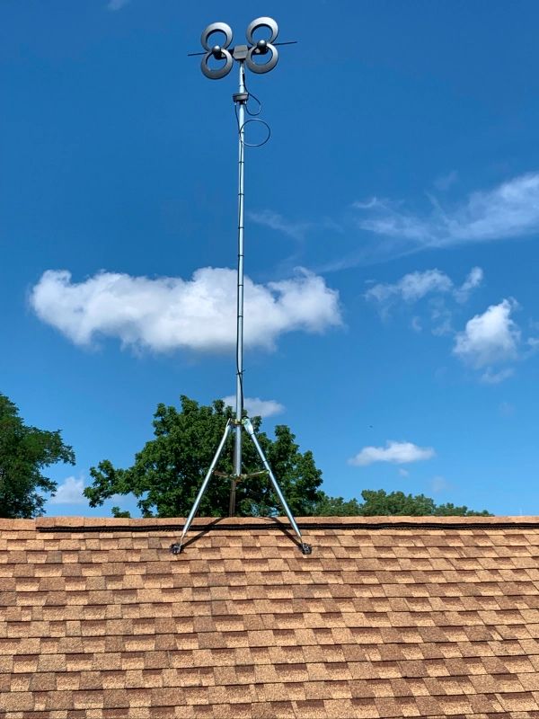 A weather station with anemometers on a rooftop, set against a blue sky with clouds.