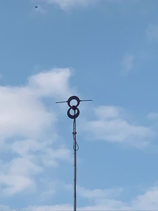 Antenna tower with two circular elements against a partly cloudy blue sky.