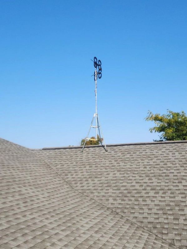 Wind speed sensor on a roof against a clear blue sky.