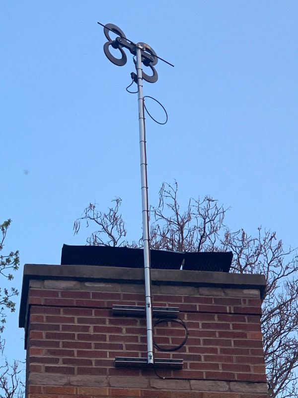 TV antenna on a brick chimney against a blue sky.